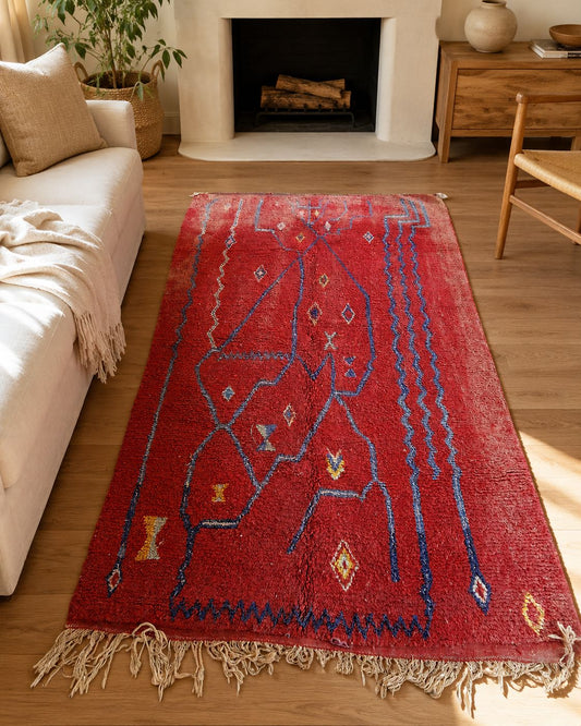 Red and blue Moroccan rug styled in an eclectic living room.