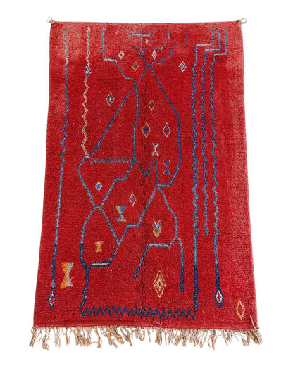 Red handmade Moroccan rug with dark blue abstract lines and geometric motifs. 