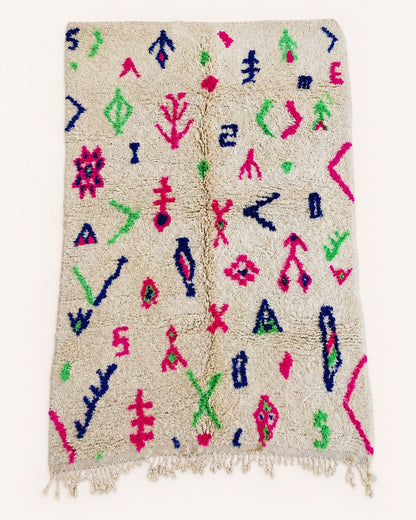 Flat view of an ivory wool rug with scattered colorful geometric symbols. 