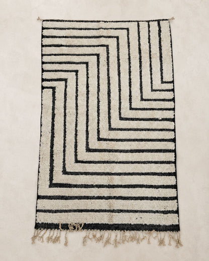 Front view of a rectangular cream rug with nested angular black lines. 