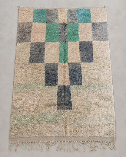 Front view of an ivory Moroccan rug with irregular green and gray squares. 