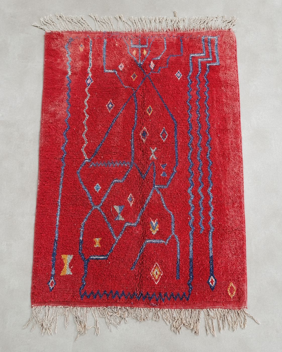 Front view of a rectangular red rug with freeform blue geometric details. 