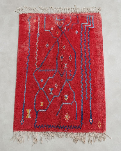 Front view of a rectangular red rug with freeform blue geometric details. 