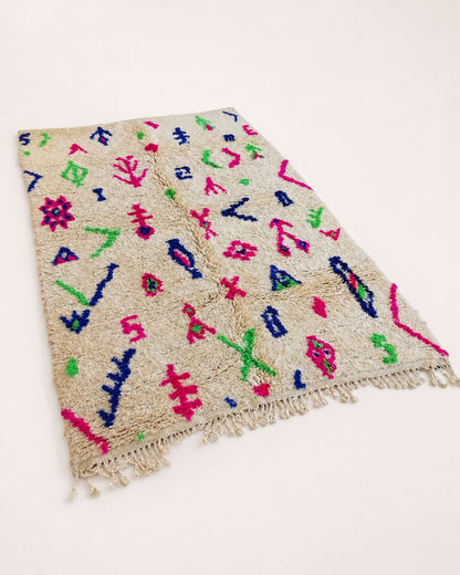 Close-up of the textured ivory wool surface and colorful handmade motifs. 
