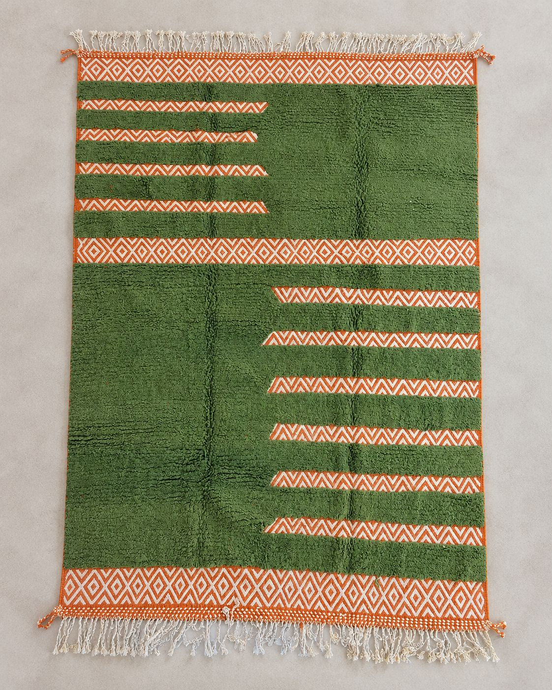 Front view of a green geometric rug with cream diamond and zigzag motifs. 
