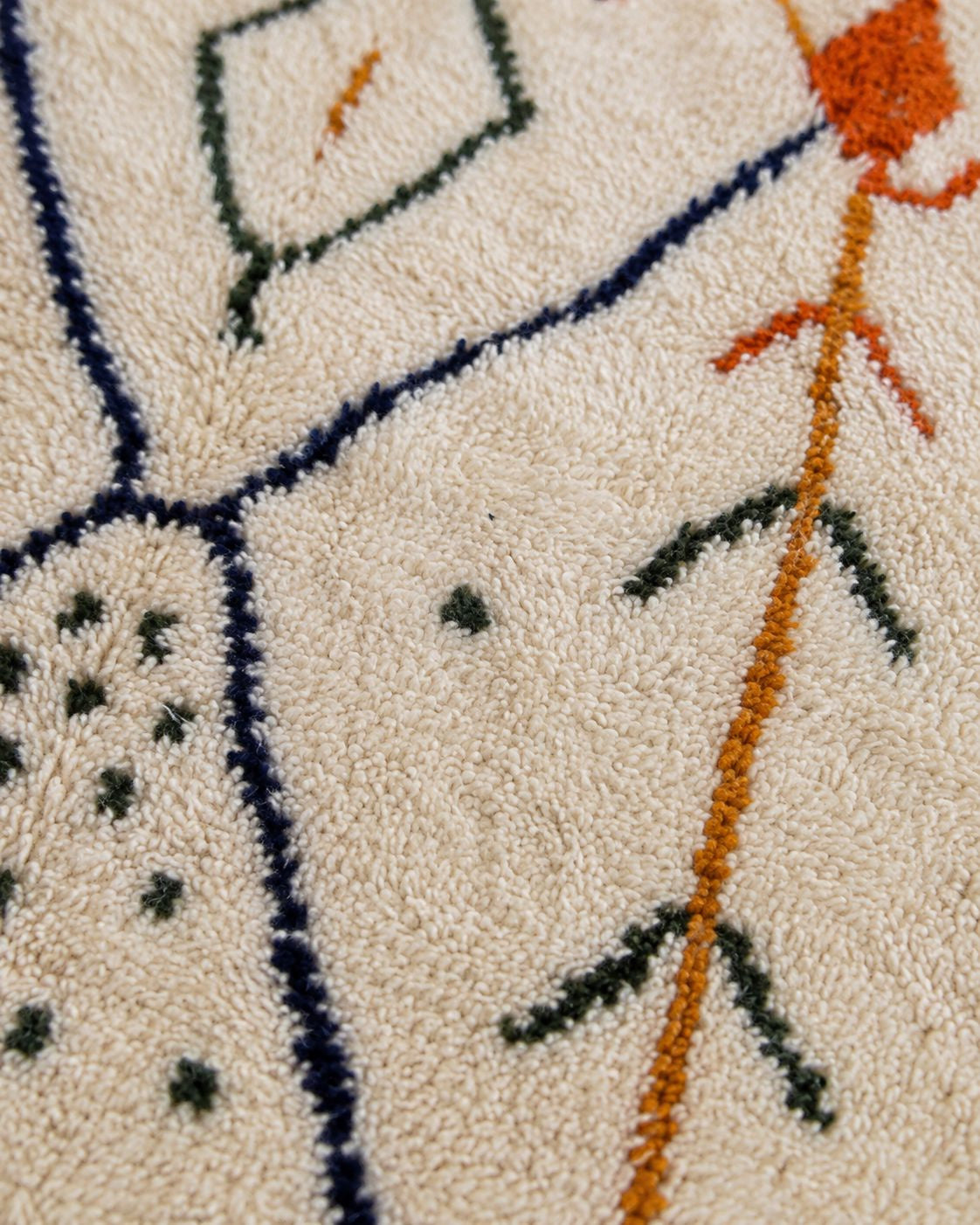 A close-up shot focusing on the knotted cream tassels finished along the bottom edge of the Moroccan rug.