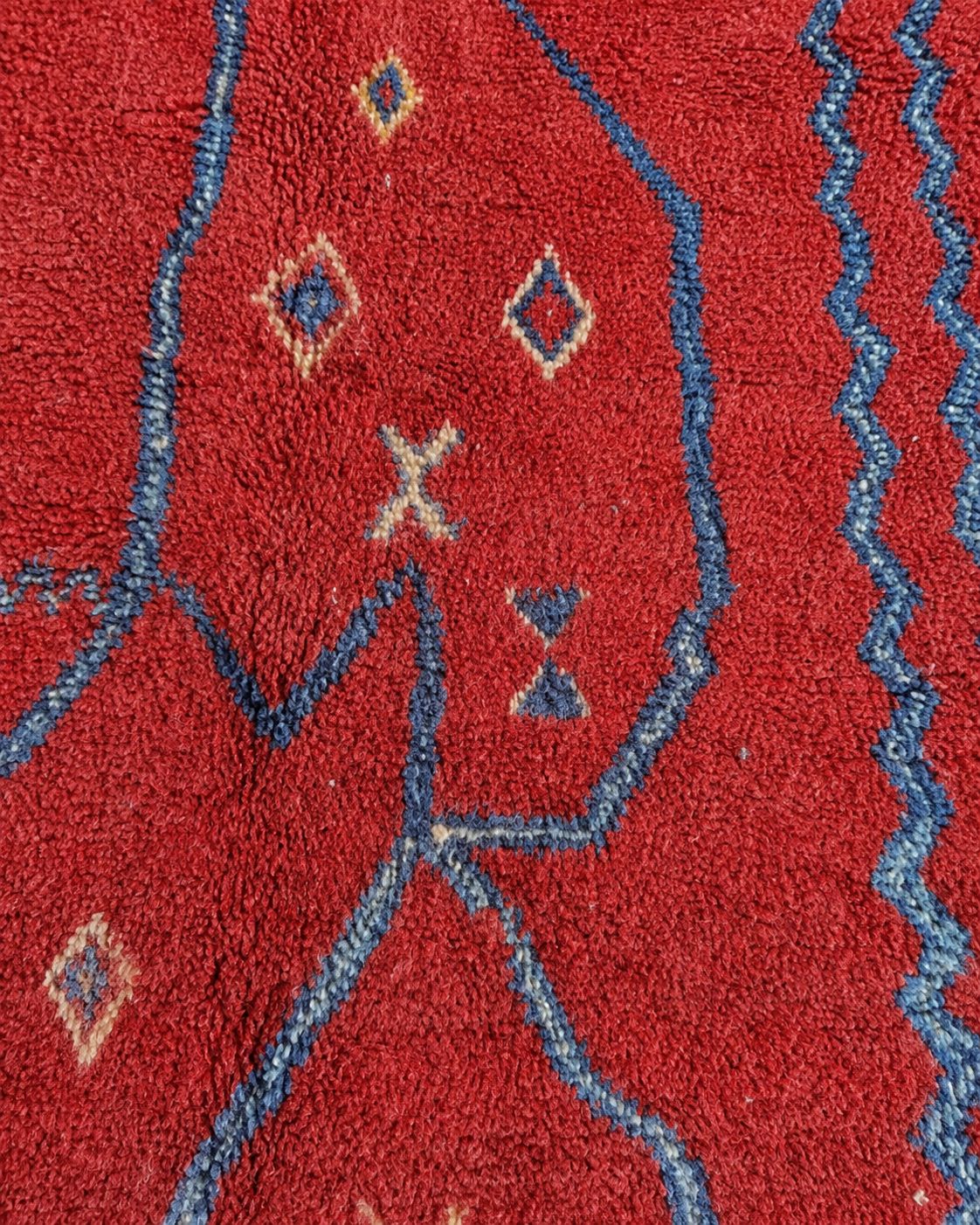 Close-up of the textured red surface and handmade blue linework. 