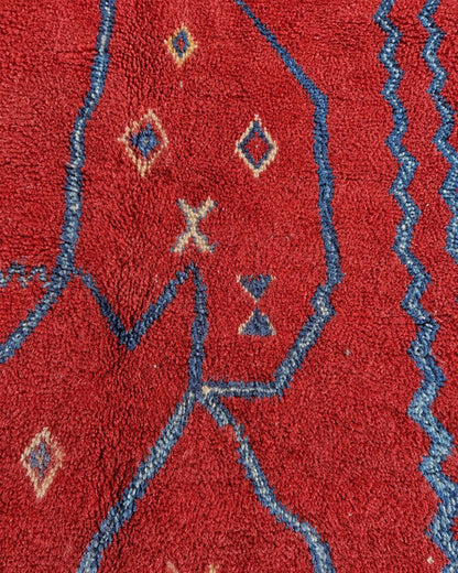 Close-up of the textured red surface and handmade blue linework. 