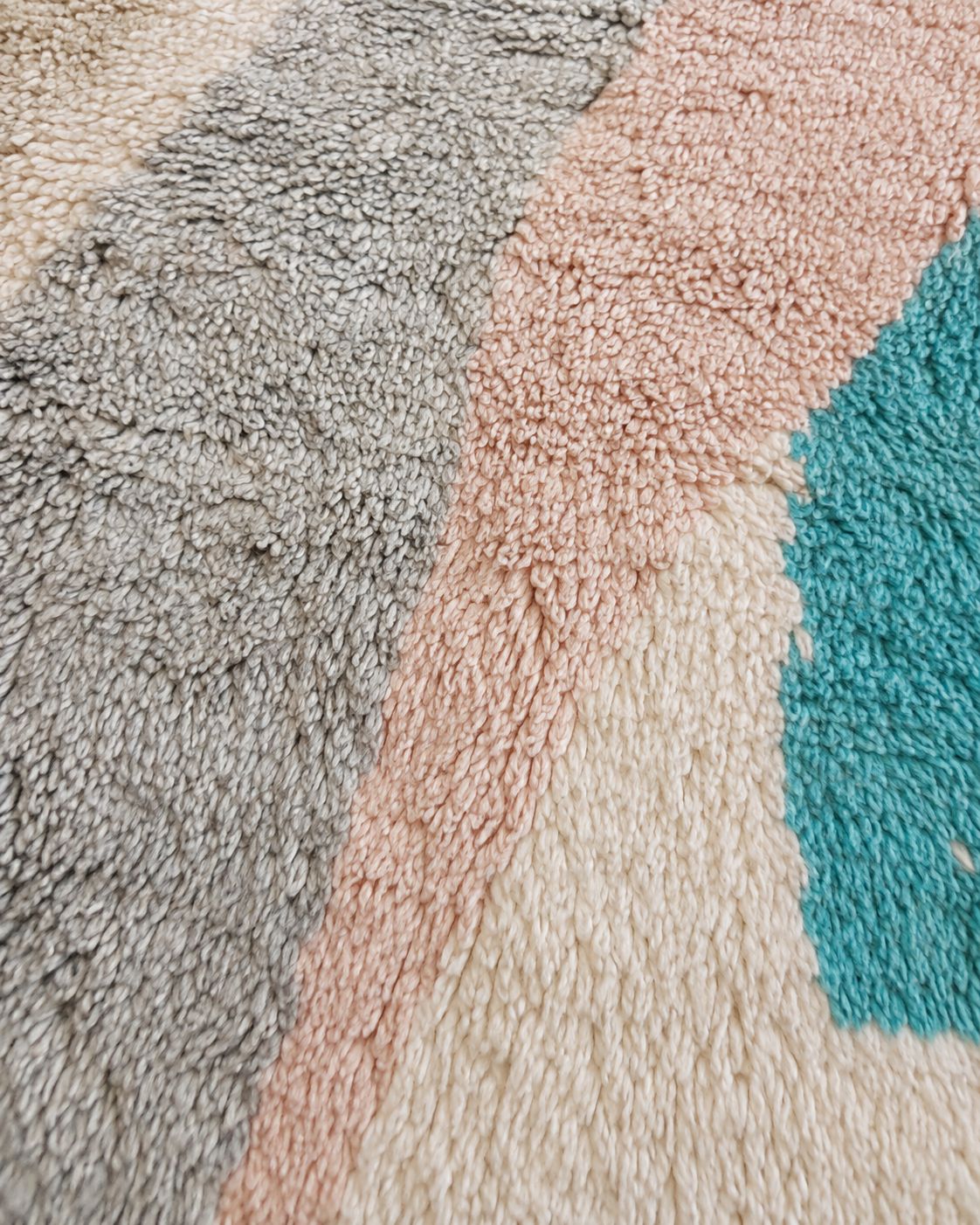 Close-up of the textured wool pile and soft abstract color details. 