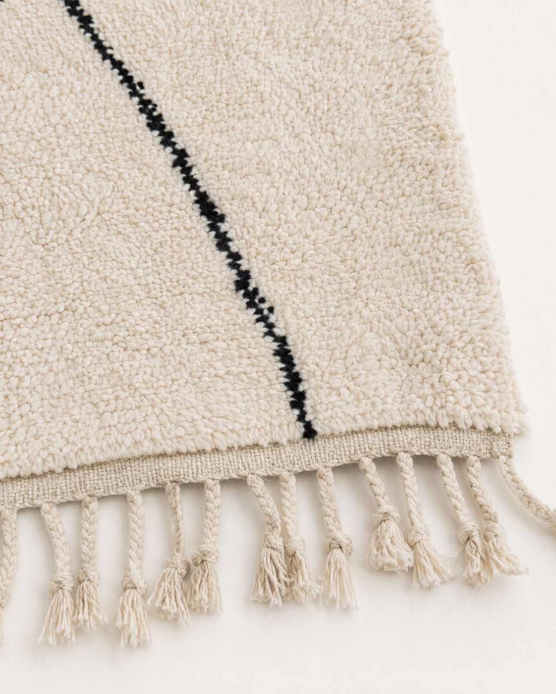 Cream tassel fringe along the short edge of the Moroccan wool rug. 
