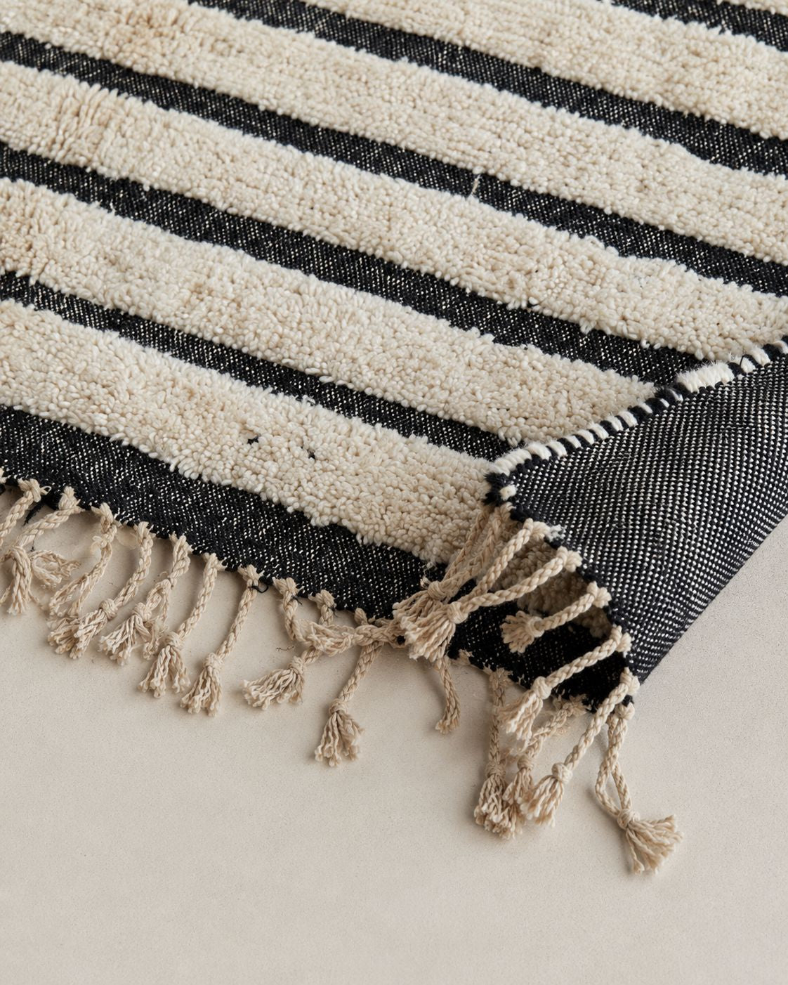 Cream tassel fringe along the short edge of the Moroccan wool rug. 