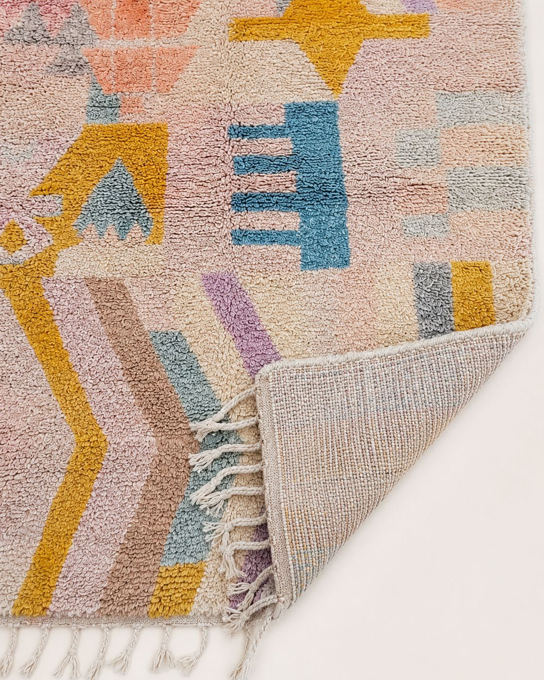 Cream tassel fringe along the edge of the handmade Moroccan rug. 