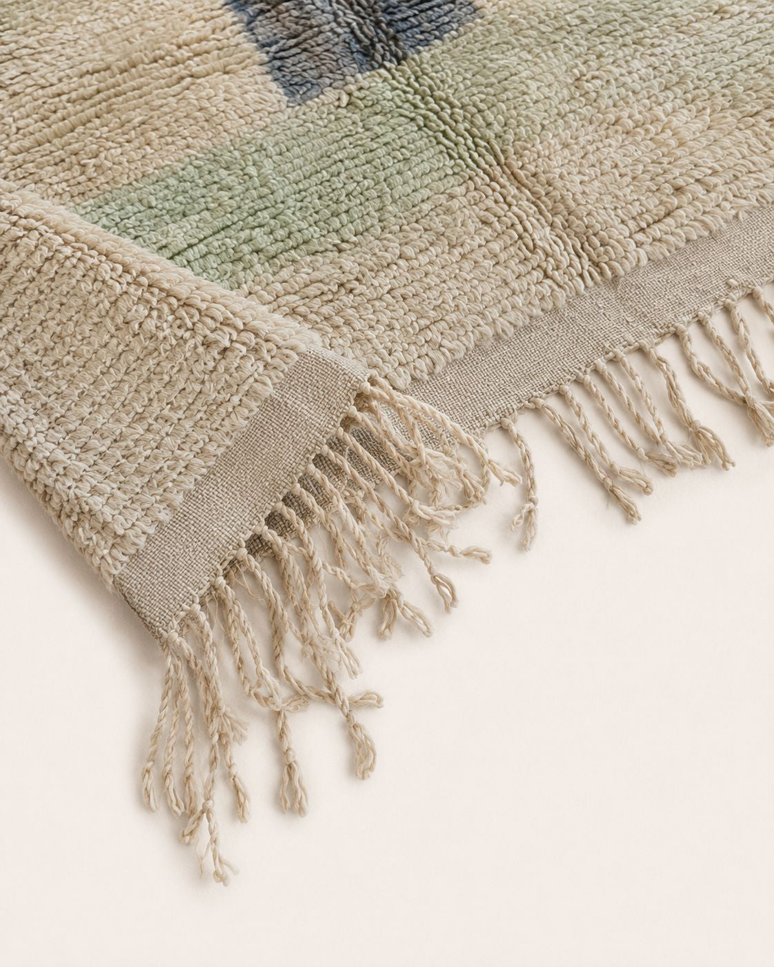 Cream tassel fringe along the edge of the vintage Moroccan rug. 