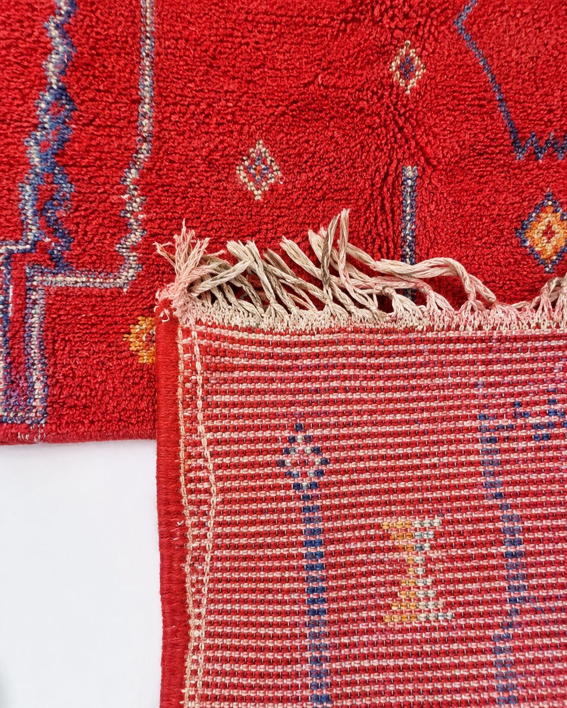 Cream tassel fringe along the short edge of the Moroccan rug. 