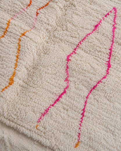 Close-up of the textured ivory wool surface and colorful handmade lines. 