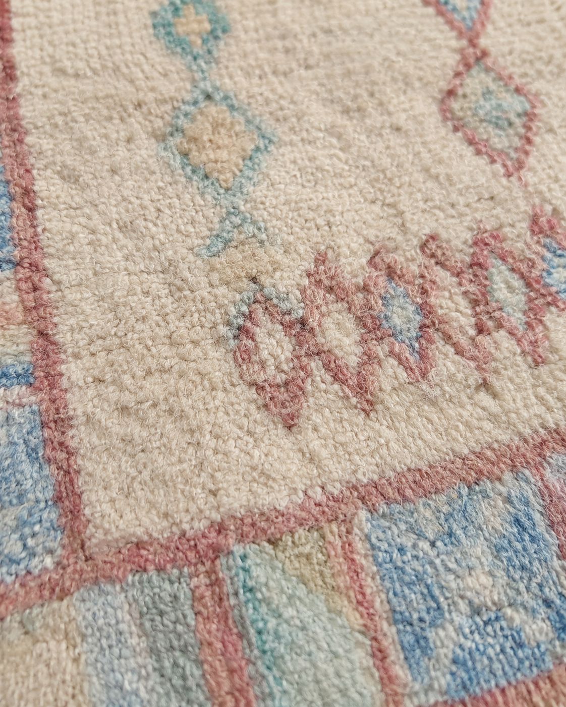 Close-up of the aged rug texture and softly faded geometric details. 