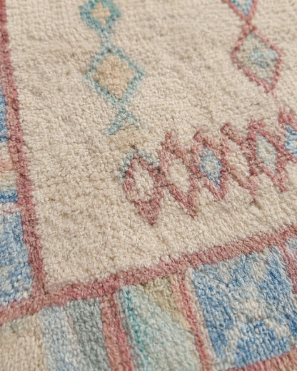 Close-up of the aged rug texture and softly faded geometric details. 
