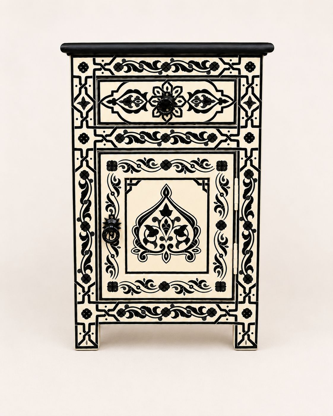 Cream and black boho nightstand styled beside a neutral upholstered bed 
