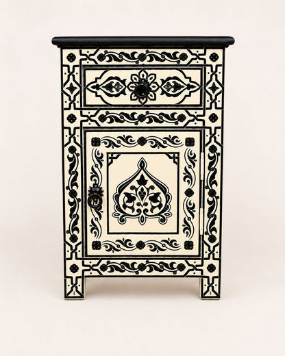 Cream and black boho nightstand styled beside a neutral upholstered bed 