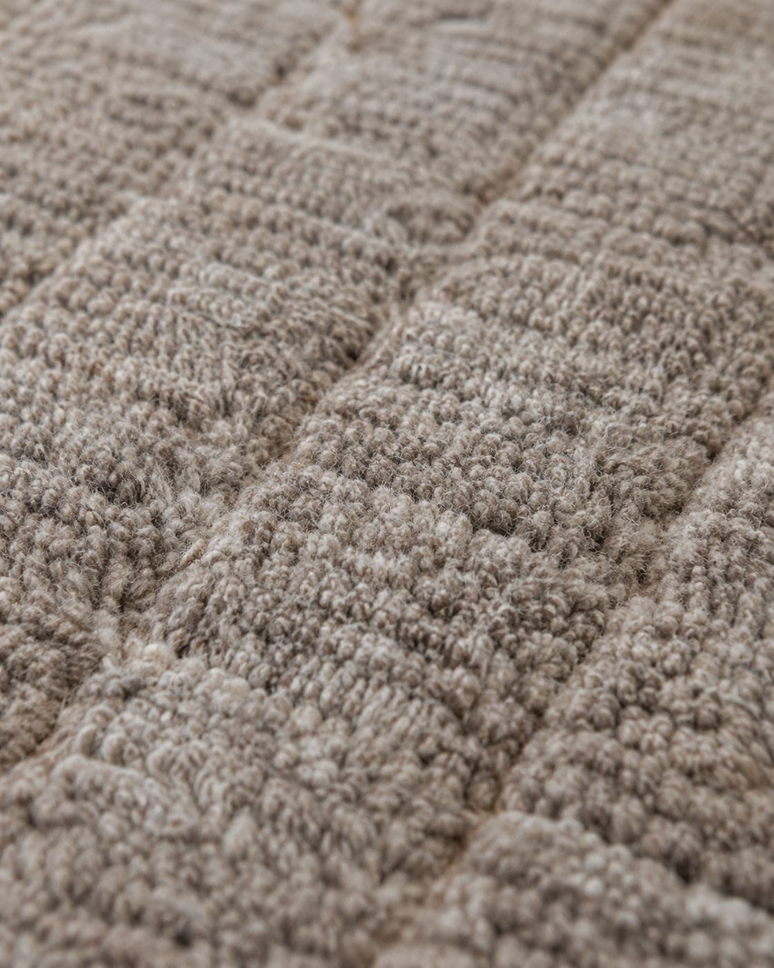 Close-up of the textured wool pile and subtle grid-inspired pattern. 