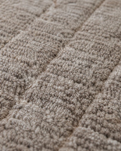 Close-up of the textured wool pile and subtle grid-inspired pattern. 
