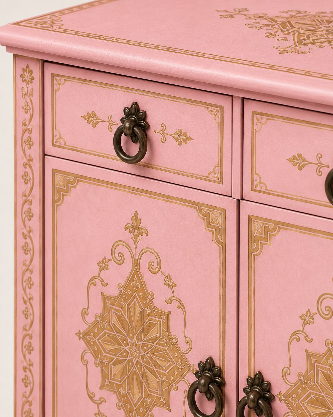 Pink cabinet with gold decorative patterns and black handles